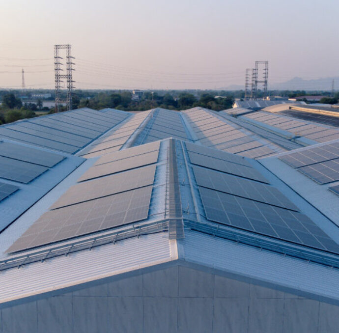 Future green energy and sustainable electricity resource concept. Outdoor focus on solar panels on rooftops or photovoltaics of factories by drone. Industrial roof with solar cell grid with blue tone.